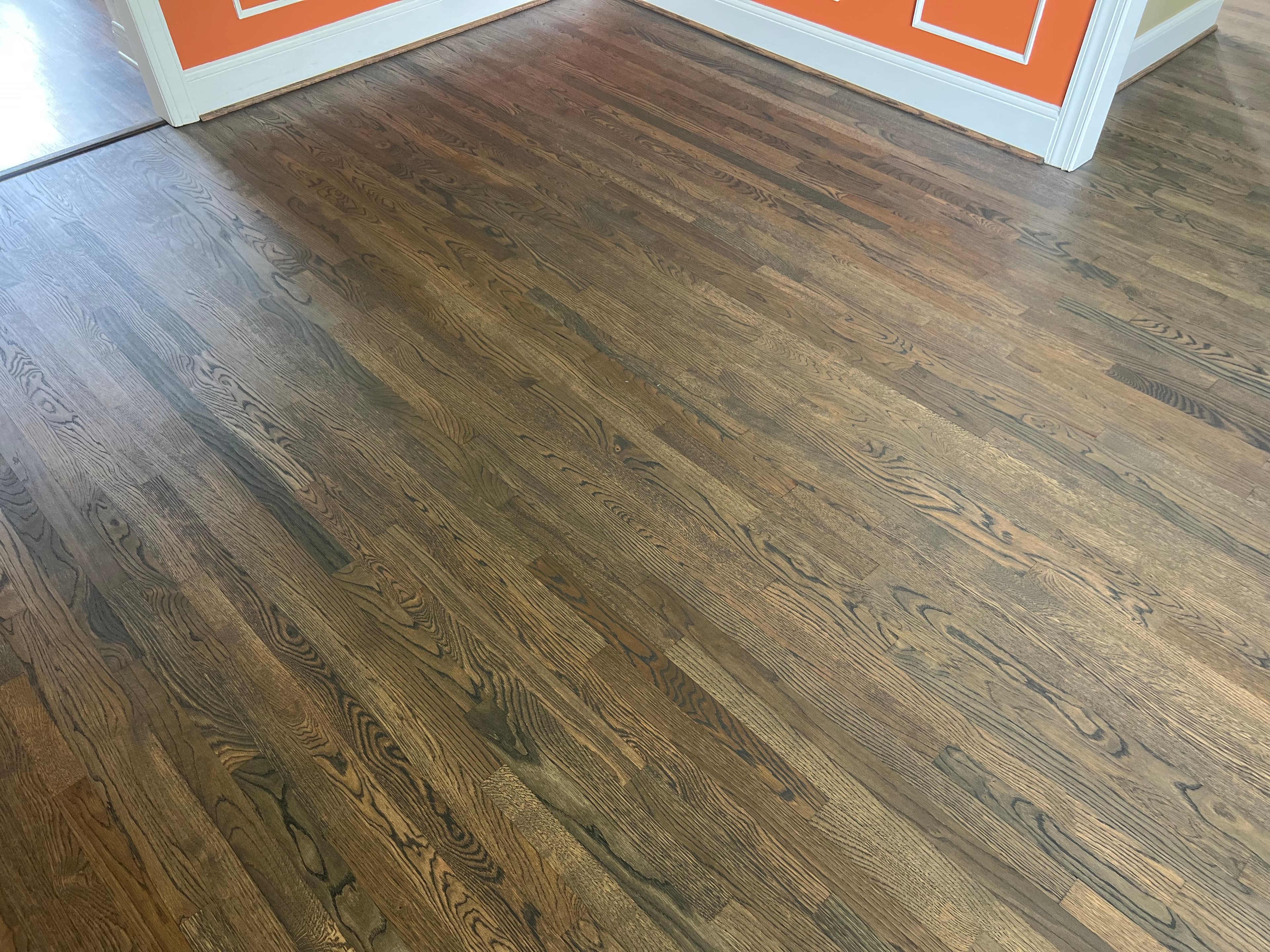 Finished white oak floors with custom hardwax oil blend in Ole Mill Stream Clayton NC, dark warm tone in room with orange accent wall