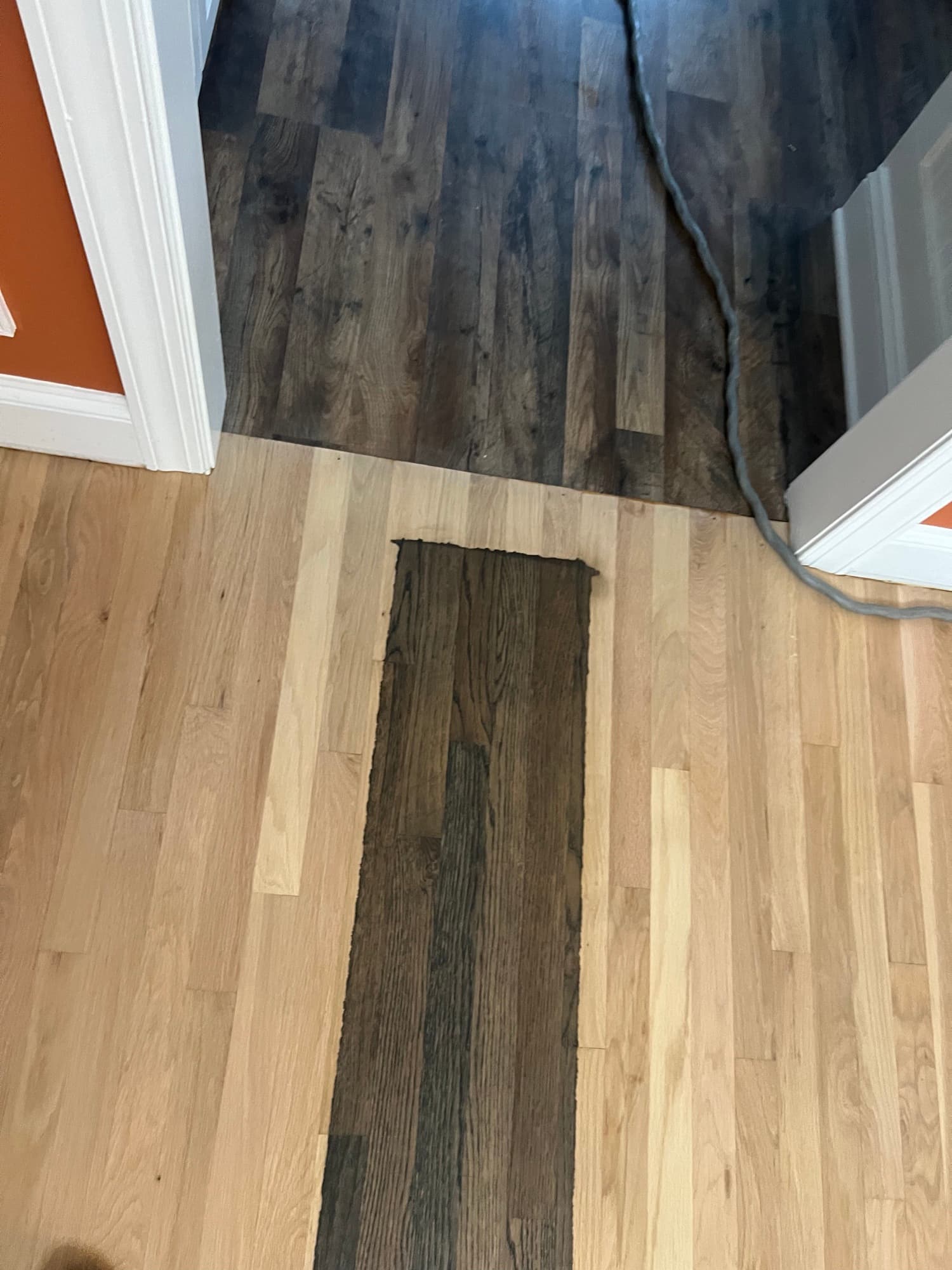 Bare sanded white oak meeting dark gray LVP at threshold in Ole Mill Stream Clayton NC, showing color match challenge between hardwood rooms and LVP rest of house
