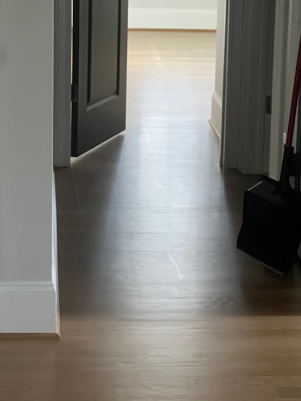 Prior contractor finish on white oak hallway showing heavy scratch marking from normal living in Raleigh NC