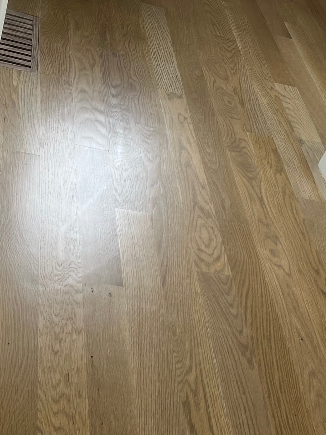 Prior contractor finish on white oak floor showing scuffs and surface damage from normal living in Raleigh NC
