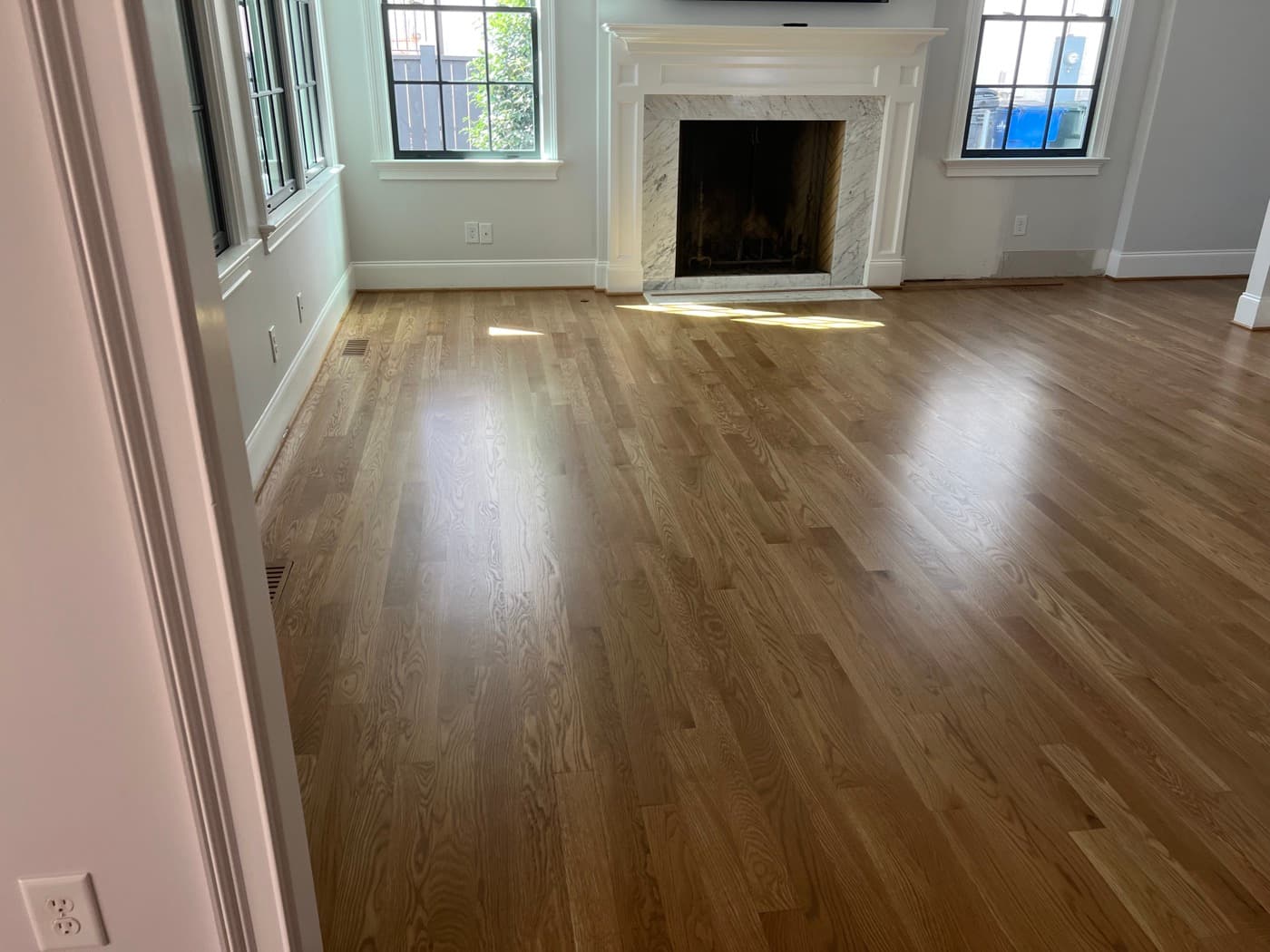 Finished 3.25-inch white oak floors with custom DuraSeal Weathered Oak blend and Bona Traffic HD in Hayes Barton Raleigh NC, wide living room with marble fireplace