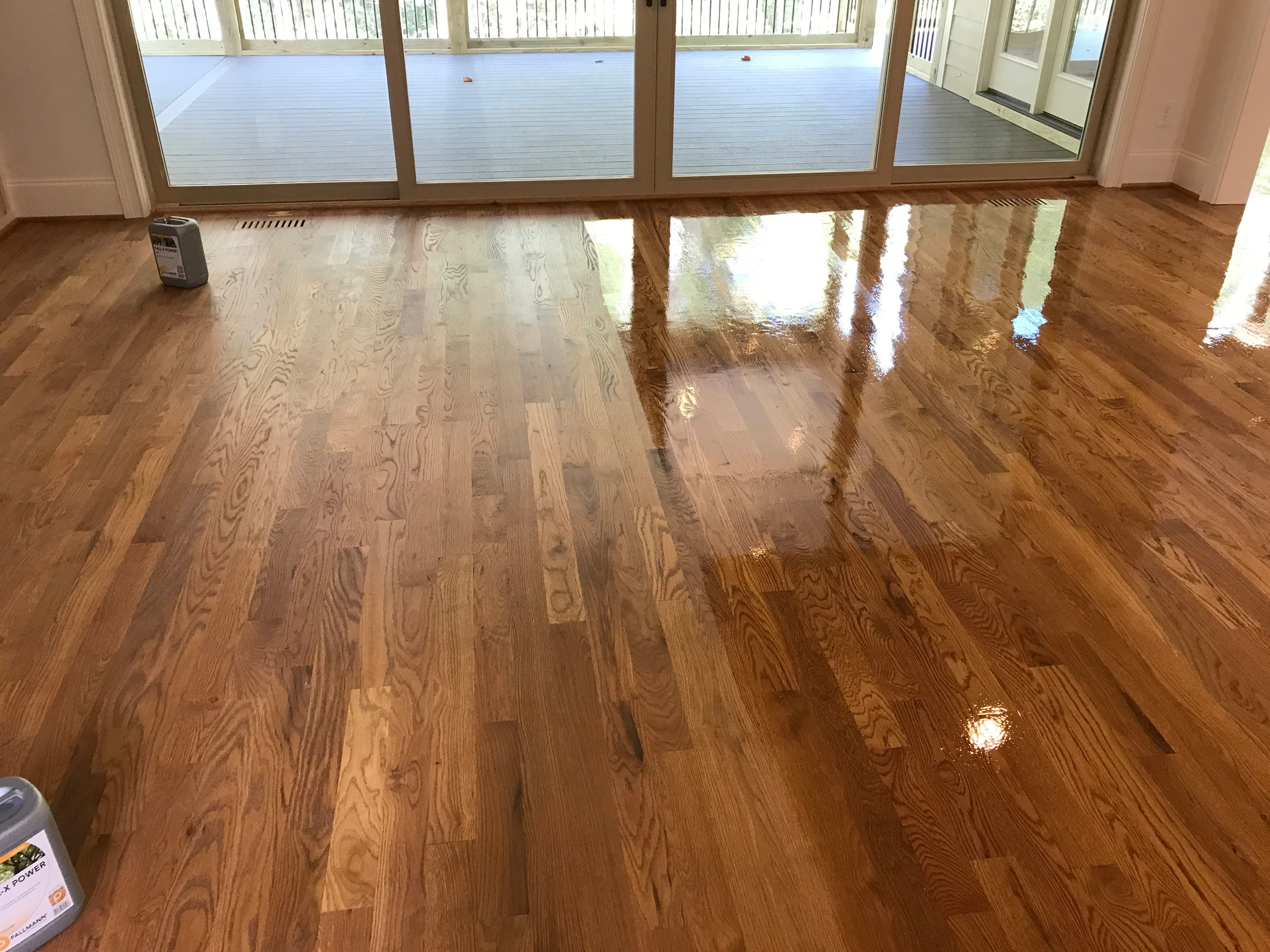 Red oak hardwood floor buff and coat in progress, Bona finish being applied near sliding glass doors