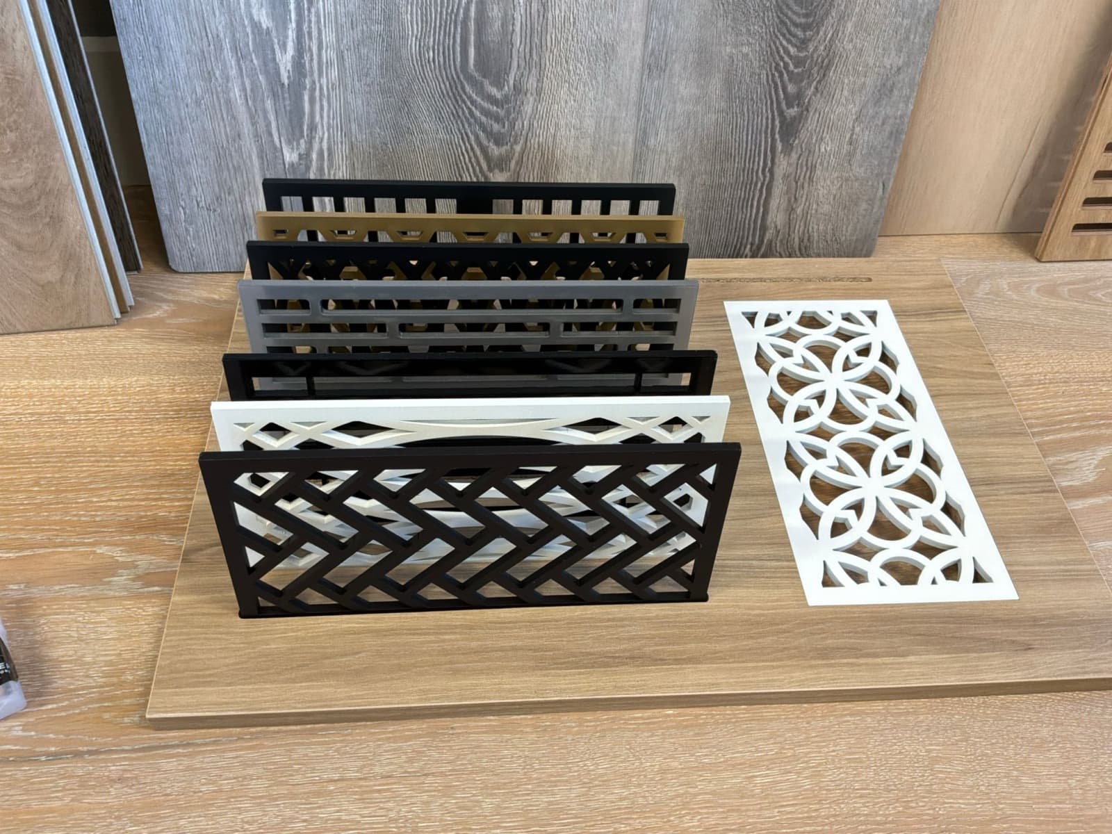 Steel flush-mount floor vent samples in several patterns and colors, with one white vent set flush into a floor panel