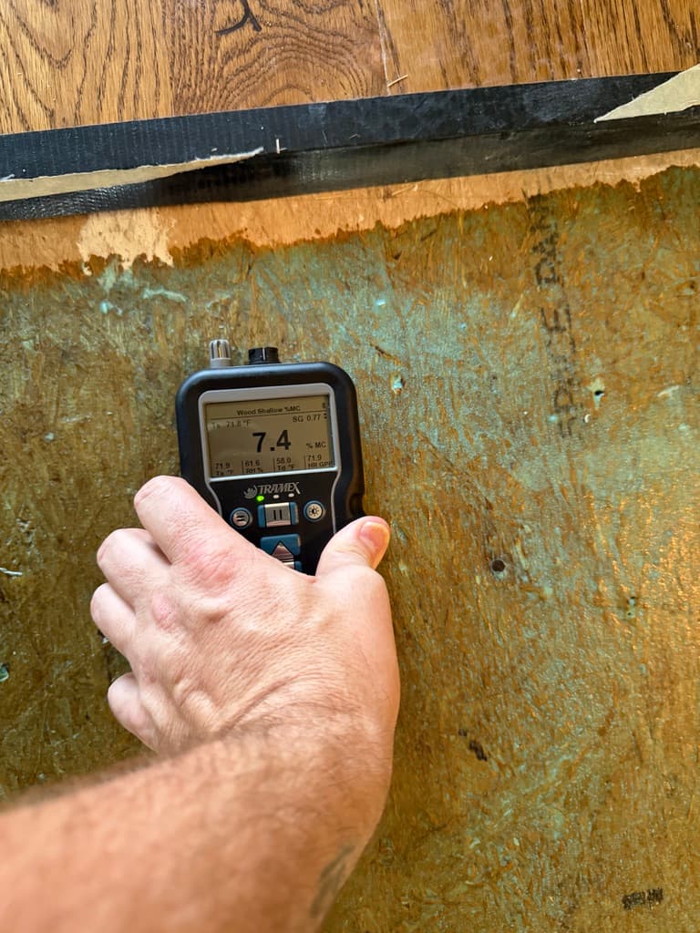 Tramex pinless moisture meter reading 7.4 percent on a subfloor before installation